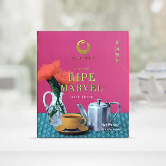 TEASPEC RIPE MARVEL Aged Ripe Pu'er Chinese Loose Leaf Pu'er Tea box with a net weight of 50g, comes in 5g Sachets x 10 per box. The front of the box design is a dark carnation pink color with a faded jade color patterned tablecloth that has a jug shaped glass vase with red flowers. A stainless-steel designer silver teapot with a tall handle and one orange porcelain teacup in front on a saucer. The Chinese name of the tea is 熟普洱