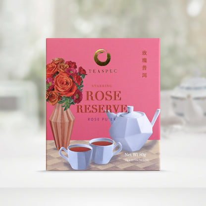 TEASPEC ROSE RESERVE Rose Pu'er  Chinese Loose Leaf Pu'er Tea box with a net weight of 80g, comes in 8g Sachets x 10 per box. The front of the box design is a pink rose color with a beige square geometric patterned tablecloth that has a designer vertical striped vase with various flowers, mainly roses. A designer white porcelain teapot with a unique handle and 2 matching teacups in front. The Chinese name of the tea is 玫瑰普洱