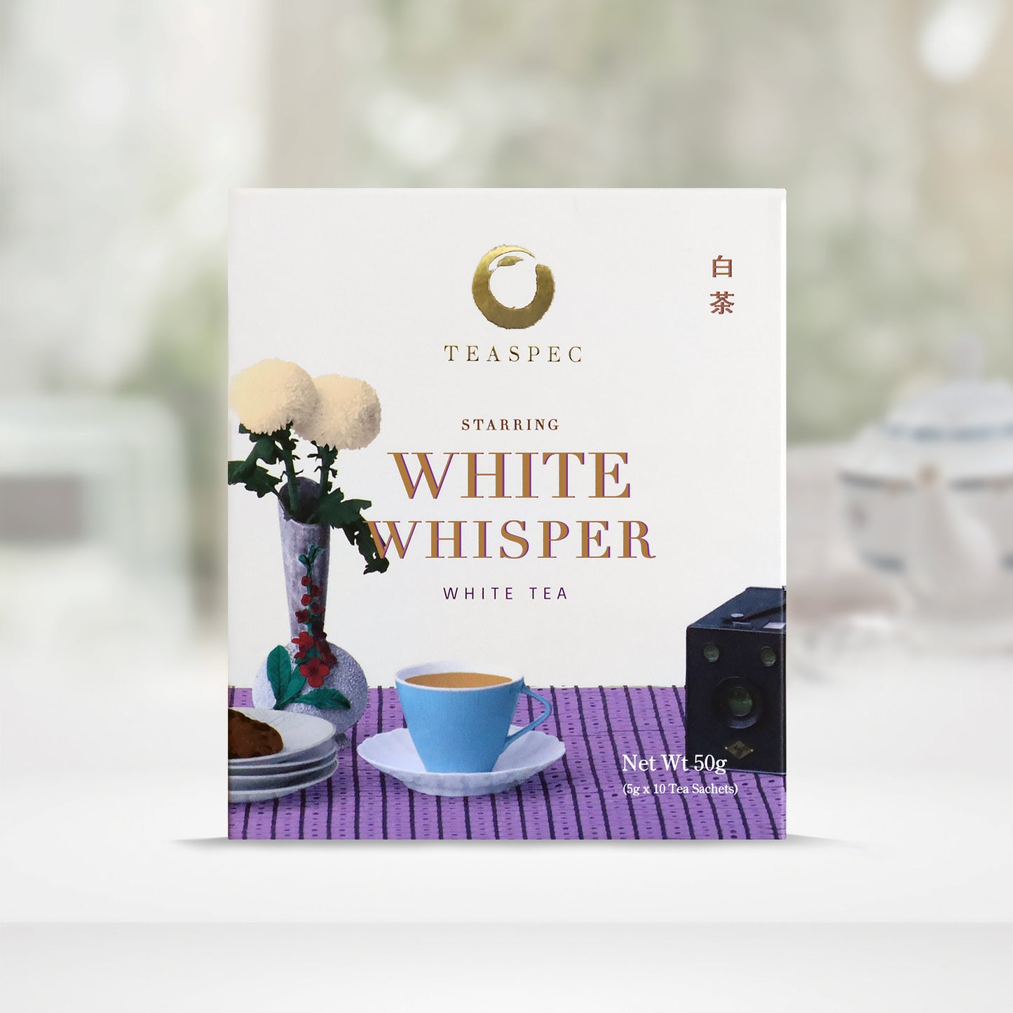 TEASPEC WHITE WHISPER White tea Shou Mei Tea box with a net weight of 50g, comes in 5g Sachets x 10 per box. The front of the box design is a floral white color with a striped light purple pattern tablecloth with slim neck floral porcelain vase with Chrysanthemum flowers. A portable retro device and a blue teacup and some plates. The Chinese name of the tea is 白茶